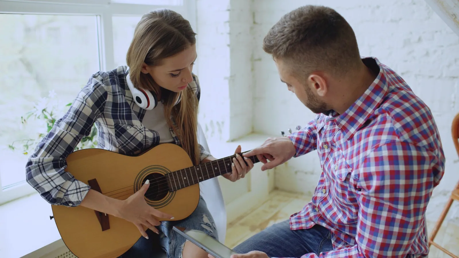 A guitar teacher guiding a student's fretting hand during a lesson